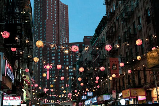 Chinatown street in New York City at night with strings of red lanterns hanging across the street