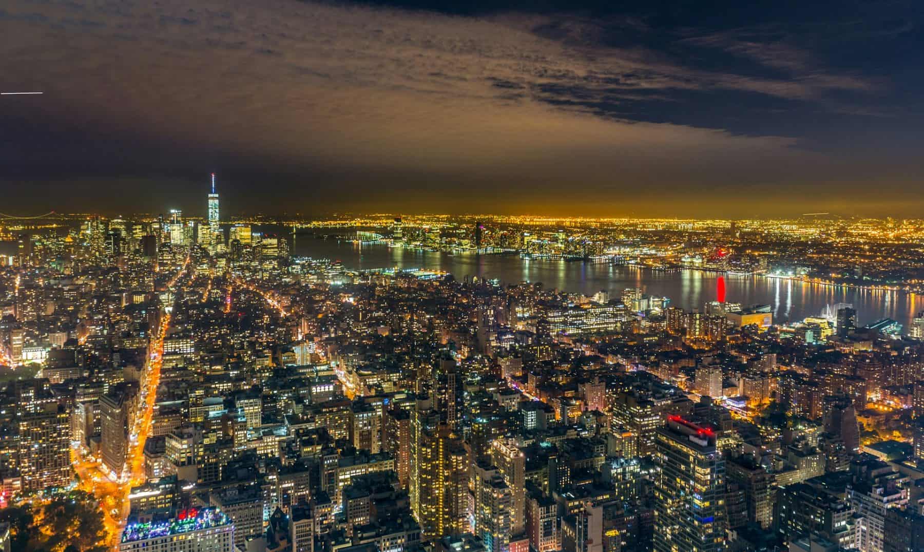 an aerial view of NYC at night showing midtown and lower manhattan and the hudson river