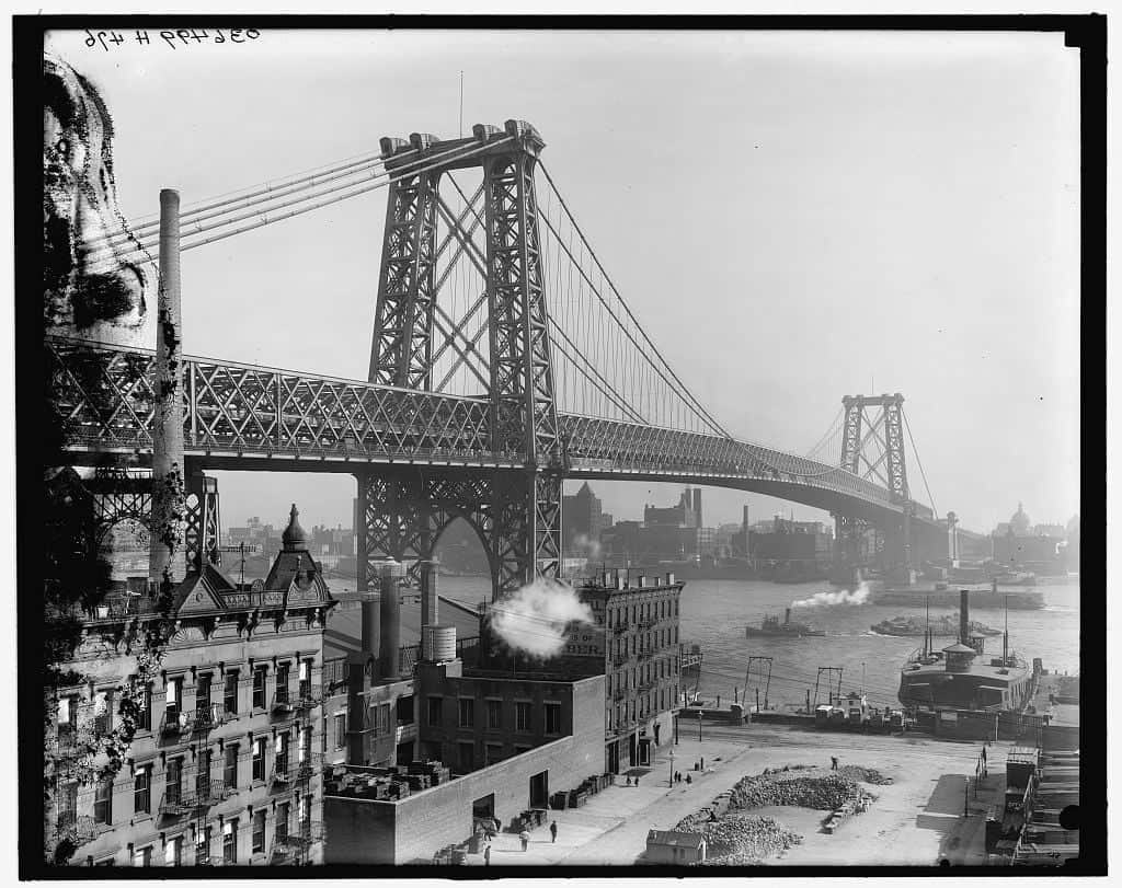 a black and white photo from 1903 of the WIlliamsburg Bridge over the East River in New York City
