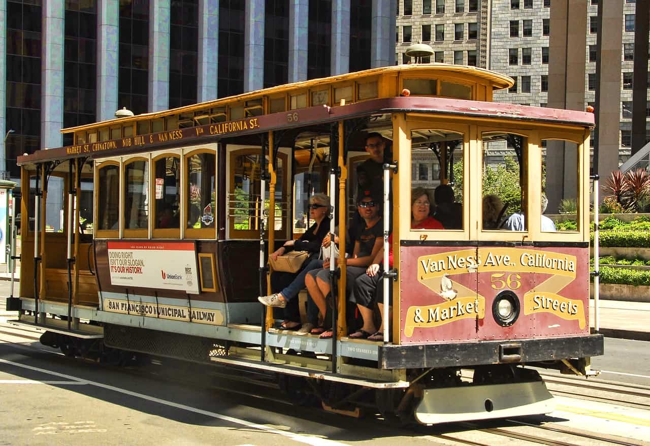A cable car with passengers rolls along the street in San Francisco