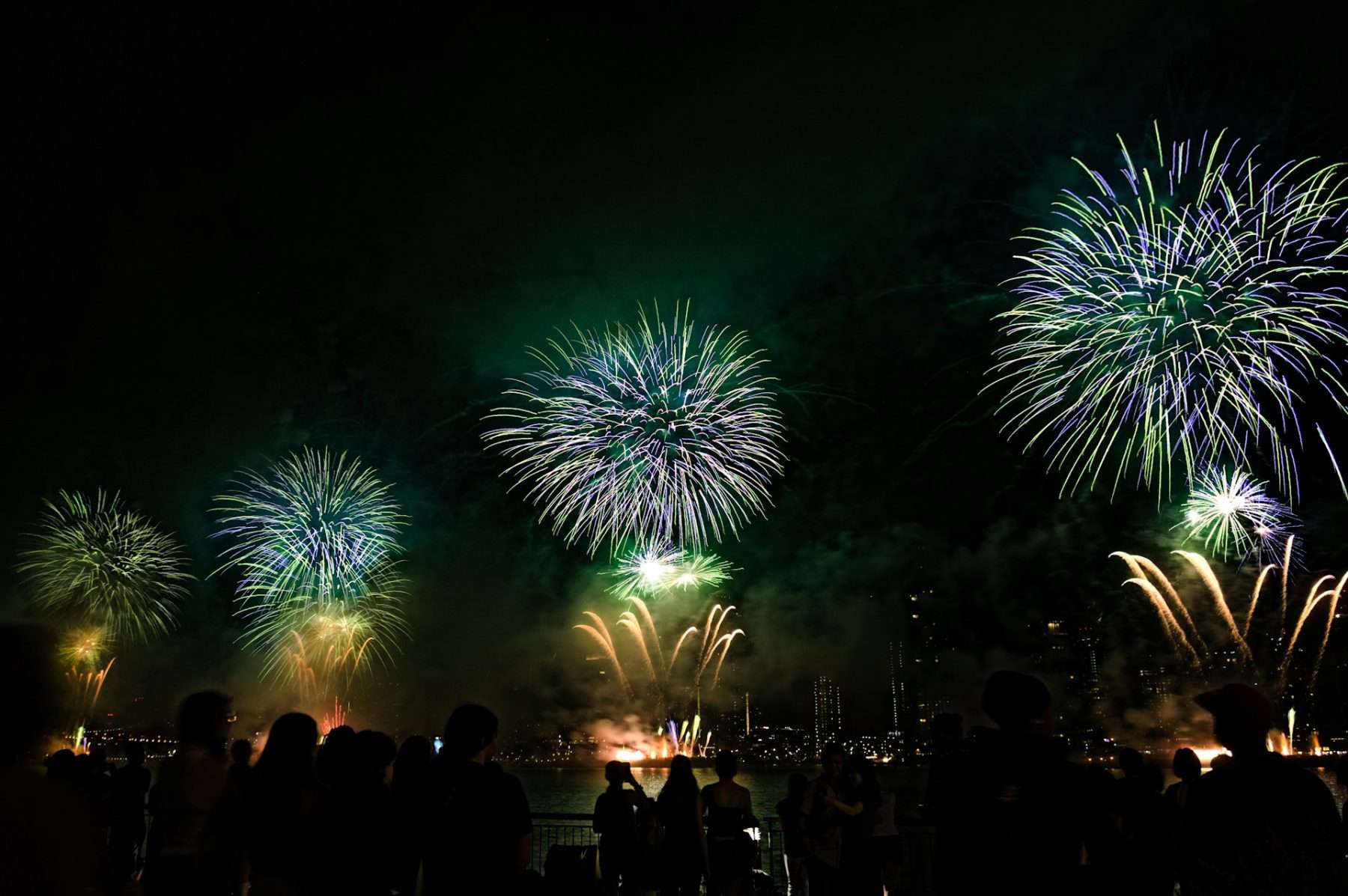 fireworks display over the NYC skyline with people watching