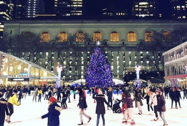 Bryant Park Winter Village Ice Skating with skaters on the ice and the christmas tree nearby