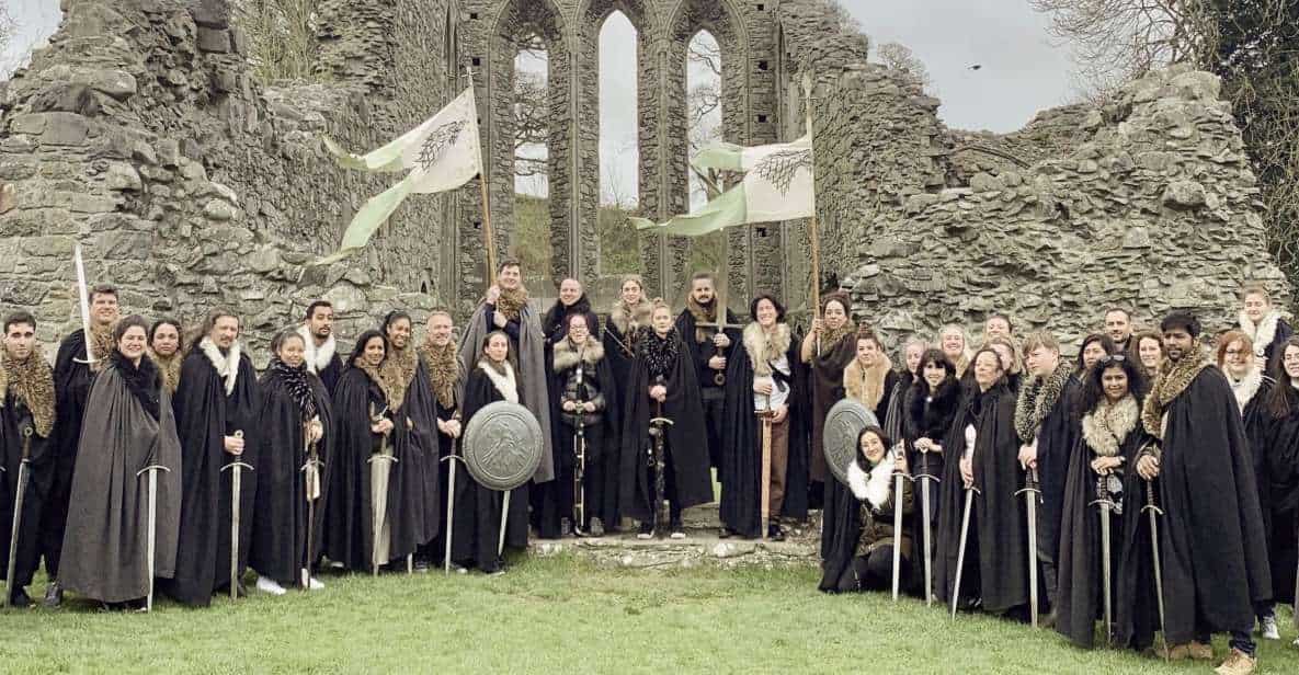 Visitors on the Game of Thrones wearing cloaks and holding swords.