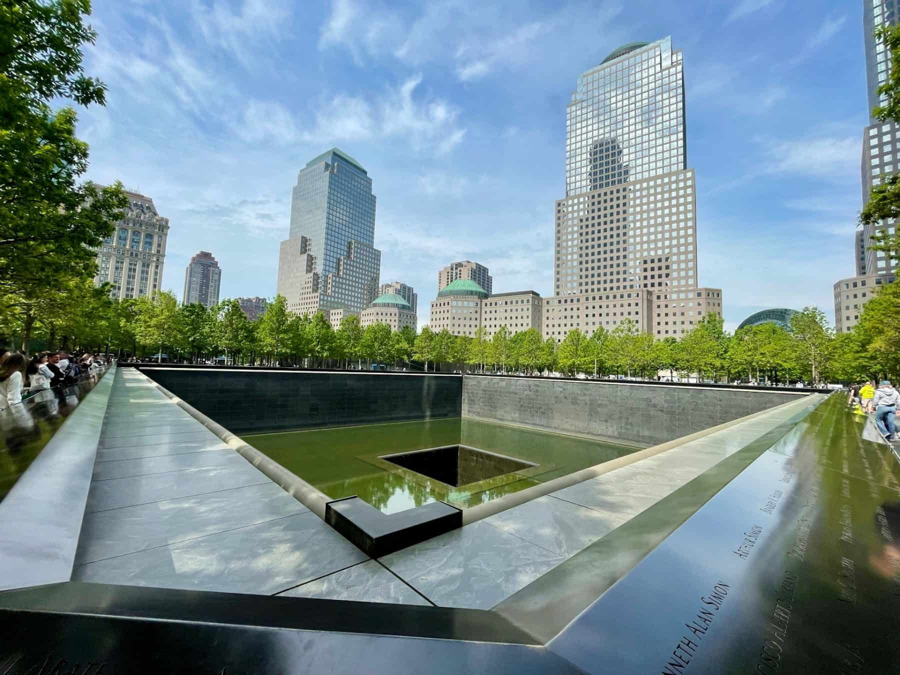 a fountain at the 9/11 Memorial in NYC with the World Trade Center buildings surrounding it